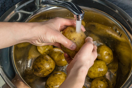 人的手洗生土豆照片