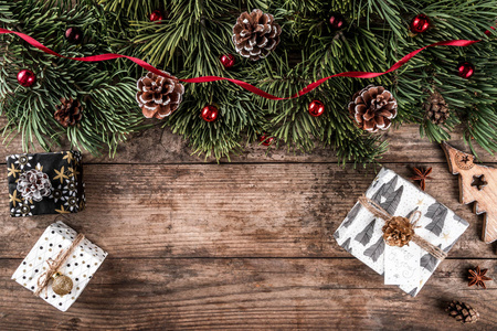 圣诞冷杉分枝在假日木背景与礼品盒, 松果, 红色装饰。圣诞节和新年主题。平面布局, 顶部视图