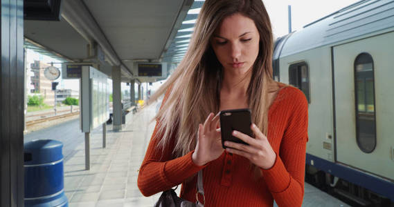 在火车站时, 年轻女子从钱包里拿出电话发短信
