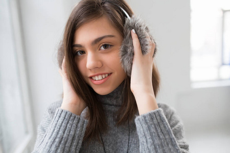 十几岁的女孩，用蓬松的耳机听音乐在白色的房间里