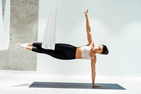 有吸引力的强大的女性练习反重力瑜伽在演播室的吊床