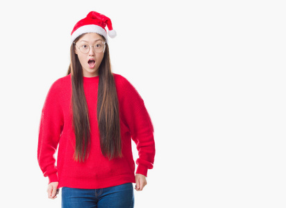 年轻的中国女人在孤立的背景上戴着圣诞帽害怕和震惊与惊喜的表情, 恐惧和兴奋的脸