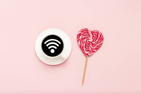 白色杯与黑色咖啡, 粉红色心形棒棒糖, 在粉红色的背景。在无线网络上签名。平面布局, 顶部视图