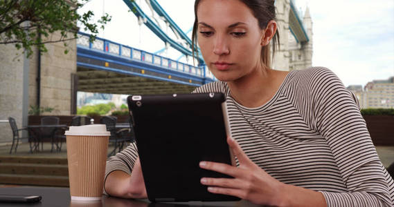 在伦敦塔桥旁, 千禧一代妇女坐在有平板电脑的咖啡馆桌旁