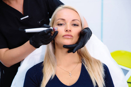 美容师在病人脸上使用水力剥离装置进行手术。用新技术清洁和振兴妇女的皮肤。临床美容理念