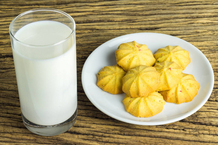 加冷在木制背景下, 在盘子里放饼干, 加一杯冷牛奶照片