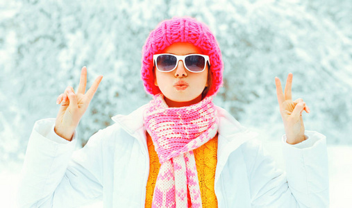 时尚酷女孩在五颜六色的针织帽子, 围巾有乐趣在雪的背景