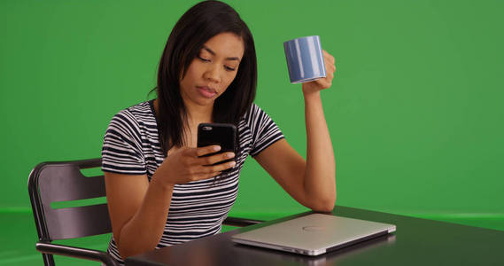 非洲裔美国妇女在咖啡馆与笔记本电脑使用手机在绿色屏幕上