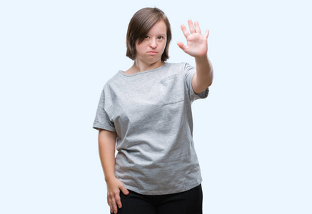 年轻成年妇女与唐氏综合征在隔绝的背景下做停止唱歌与手掌的手。脸上带有否定和严肃手势的警告表达式