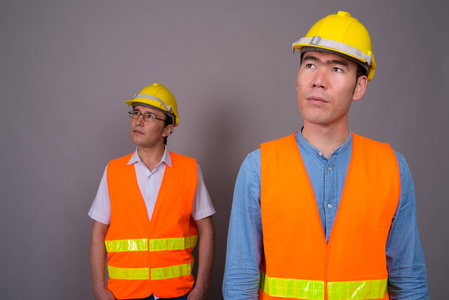 两名年轻的亚洲男子建筑工人在一起对抗灰色巴