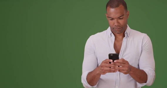 休闲黑人男性使用智能手机在绿色屏幕上的文字