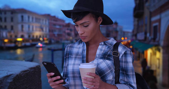 现代非洲年轻女子在威尼斯浏览网络后, 得到咖啡
