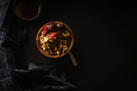 在木碗里放覆盆子和黑莓的燕麦, 在黑色桌子上放一杯咖啡