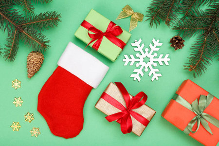 圣诞装饰。圣诞老人的靴子, 礼品盒, 冷杉树枝与锥和雪花在绿色的背景。顶部视图。圣诞贺卡概念