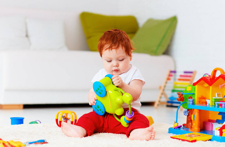 可爱的婴儿红发男宝宝玩玩具在家里
