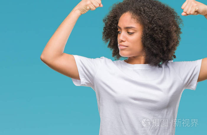 年轻的美国黑人妇女在孤立的背景下显示手臂肌肉微笑自豪.健身理念