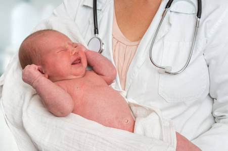 使用听诊器的儿科医生将新生儿抱在怀里