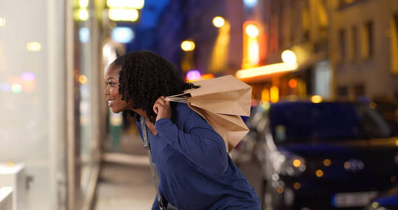 一天晚上, 黑人女子看着城市里优雅的橱窗展示购物
