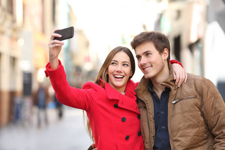 冬天, 幸福的夫妇在街上用智能手机自拍