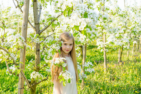 一个美丽的小女孩穿过 s 开花花园