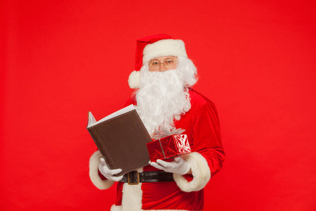 圣诞老人在红色的背景上读旧书。圣诞节