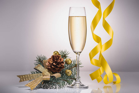 近距离查看香槟杯, 圣诞装饰和灰色背景上的五彩纸屑