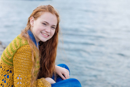 红头发的女孩坐在海边上的雀斑