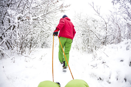 一个人把孩子抱在雪橇上。父亲冬天和儿子散步。爸爸把孩子滚到雪橇上。穿过冬天的森林。覆盖雪的公园