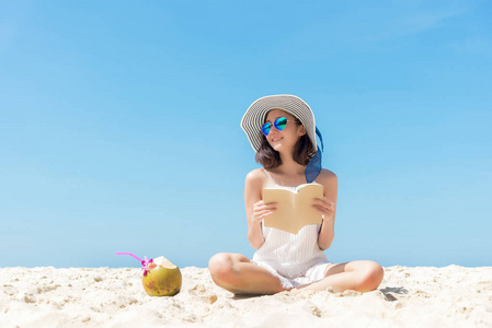 暑假。闻到亚洲女人在沙滩上放松和看书的味道, 所以在节日夏天快乐而豪华, 蓝天的背景。旅行和生活方式概念