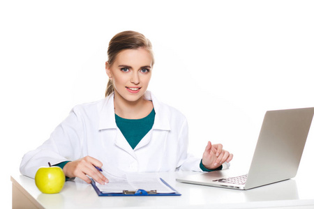年轻女学生医生坐在白色背景上的一台笔记本电脑