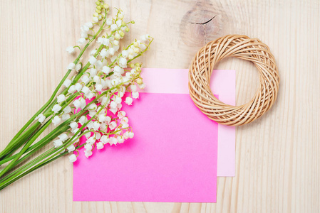 束铃兰和空粉红色纸上木制背景