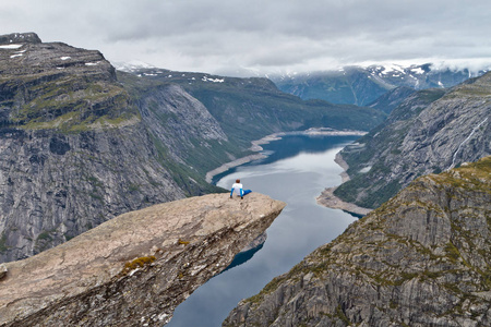 男人坐在 Trolltunga 岩石 巨魔的舌头岩 和看挪威山风景