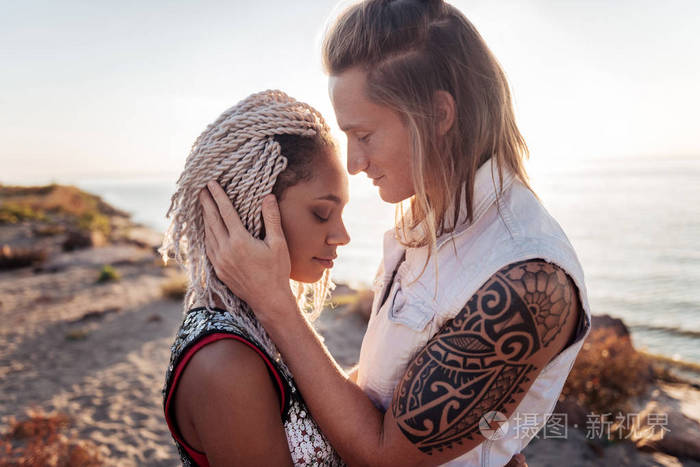 金发碧眼的男子与纹身在他的手拥抱他可爱的女朋友