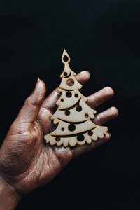 女性手拿着木圣诞树装饰在黑色背景