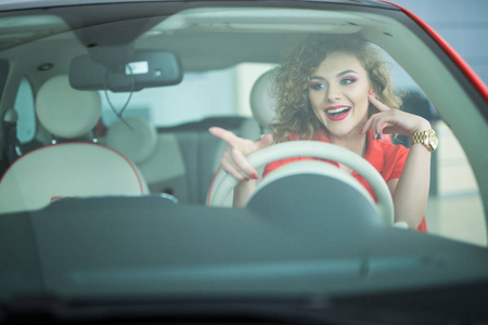 指出一边微笑的女人驾驶汽车,有魅力的女孩坐在汽车照片