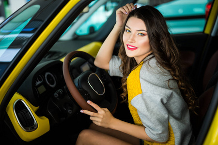 美丽的微笑女人开车黄色，有魅力的女孩坐在汽车，肖像
