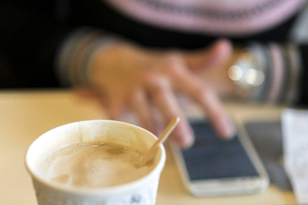 年轻女子坐在咖啡馆里用智能手机, 喝着美味的咖啡。模糊