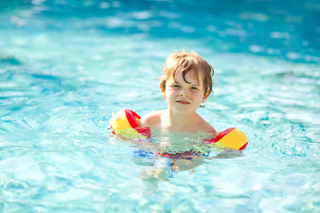 快乐的小男孩在游泳池里玩得很开心.积极快乐健康学龄前儿童学习游泳.