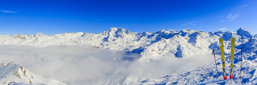 滑雪在冬天季节, 山和滑雪游览人在山顶在晴朗的天在法国, 阿尔卑斯在云彩之上