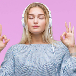 年轻的高加索妇女听音乐戴耳机在孤立的背景放松和微笑闭着眼睛做冥想