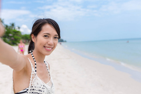 手持相机的女人采取自拍照在海滩
