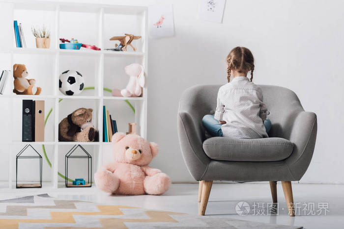 孤独的小孩坐在扶手椅上的后视镜与玩具