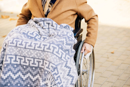 男子在街上坐在轮椅上的高级残疾男子, 腿上的格子骑在街上照片