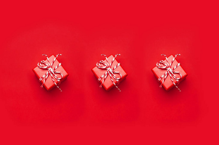 三个红色礼品盒与装饰花边在红色背景的顶部视图平躺。节日概念新年或圣诞礼品盒礼物圣诞节假期。祝贺背景与文本的空间