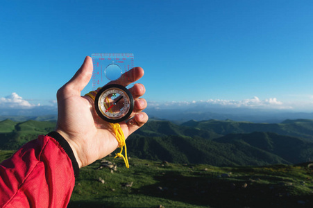 男子寻找方向与罗盘在他的手在夏天山的观点。方向搜索