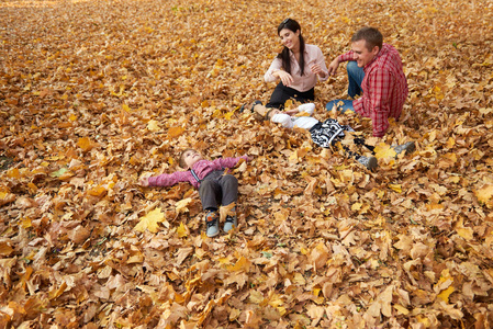 家长和孩子都坐在秋城公园里。明亮的黄色树