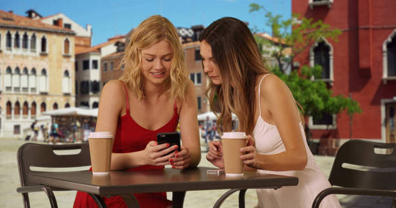 两名年轻女子穿着夏季服装, 在意大利小镇上社交, 玩得很开心