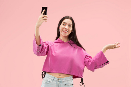 一个快乐的微笑休闲女孩的肖像显示空白屏幕移动电话在粉红色背景下隔离