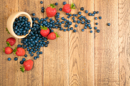 新鲜美丽的草莓和蓝莓在老式的木质背景与 Copyspace。深色木桌板纹理与成熟森林浆果顶部视图