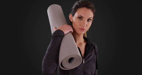 特写健康漂亮的瑜伽女孩与练习垫在深灰色背景